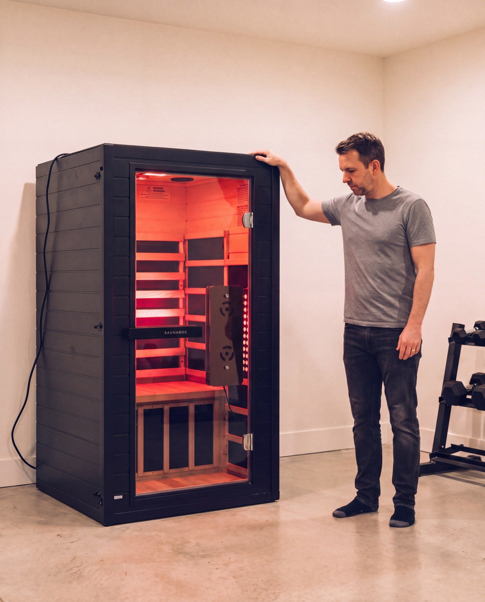 A man standing next to the SaunaBox Solara 1-person sauna to show its true size