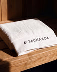 SaunaBox 100% cotton full body towel, single towel folded on a cedar sauna bench